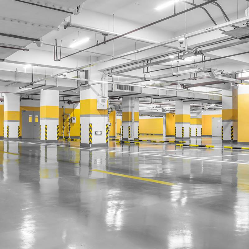 An empty underground parking garage in Oregon features yellow and gray pillars, with shiny, concrete-coated floors gleaming under the bright lighting.